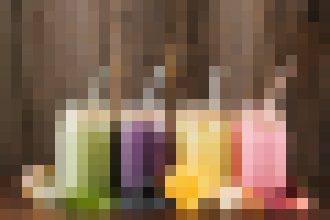 Colorful glass bottles lined up on a wooden shelf, viewed from the front.