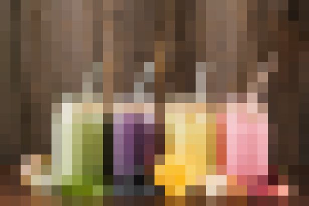 Colorful glass bottles lined up on a wooden shelf, viewed from the front.