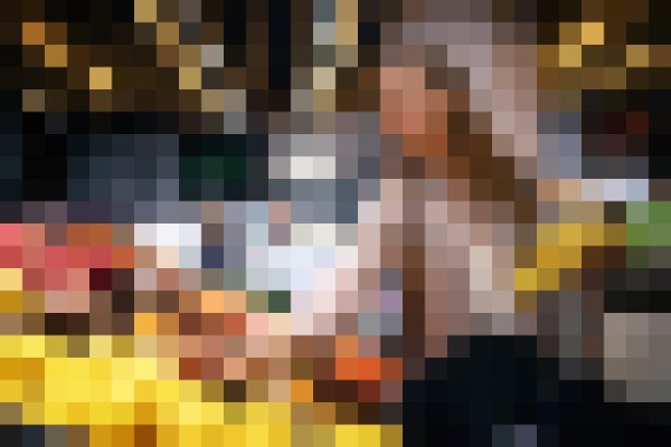 Blurred photo of a person standing behind a counter in a warmly lit bar or restaurant setting.