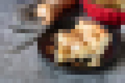 Blurry image of a round, cooked dish on a dark surface, likely a pizza or similar with cheese and toppings visible.