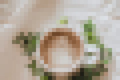 Pixelated image of a person holding a round plate or dish with brown center and green garnish in a light kitchen setting (context unclear).