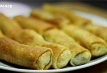 ხორცის ბლინები ნებისმიერი გურმანის გულს დაიპყრობს Plate of golden fried rolled pastries on a white plate, close-up view.