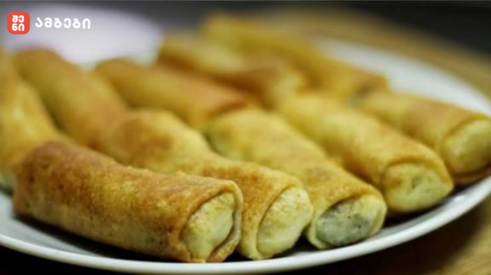 Plate of golden fried rolled pastries on a white plate, close-up view.