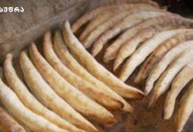 როგორ მოვამზადოთ კახური შოთის პური Rows of curved bread sticks cooling on a rustic baking sheet, with more sticks stacked in the background.