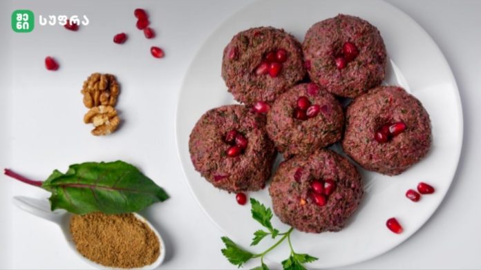 Round beetroot cutlets topped with pomegranate seeds on a white plate, with walnuts and ground spice on the side