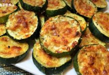 ფქვილში შემწვარი ხრაშუნა ყაბაყი Plate of baked zucchini rounds topped with melted golden cheese and herbs on a white platter