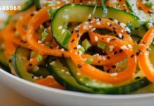 მოამზადეთ მარტივად ბულგარული წიწაკის სალათა Close-up of a cucumber and carrot salad topped with sesame seeds and chopped green onions.