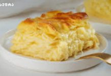 დაუვიწყარი გემო – აჩმა, რომლის გარეშეც სადღესასწაულო სუფრა არ არსებობს Golden, flaky cheesy pastry slice on a white plate with a gold spoon beside it.