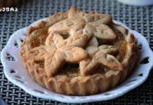 სადღესასწაულო ტარტი ჯემით Pie topped with leaf-shaped crust lattice on a white plate, set on a woven table.