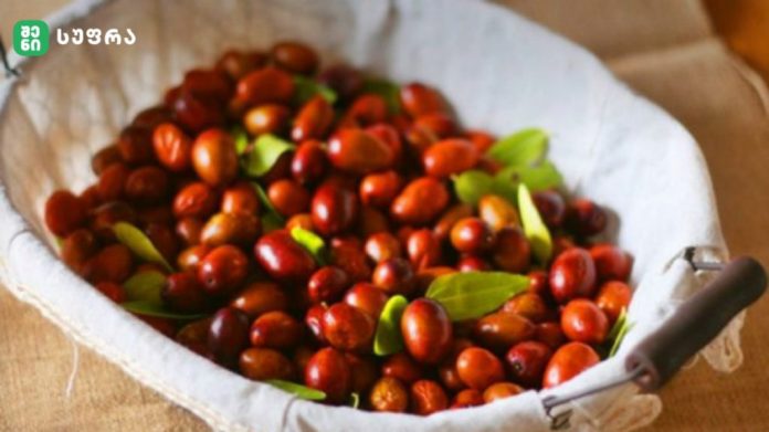 Cloth-lined basket overflowing with small red berries and a few green leaves.
