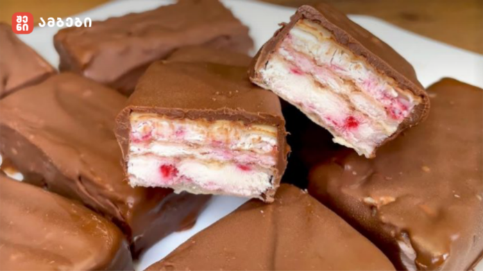 Chocolate-coated wafer bars with white cream filling and pink bits, some pieces broken open to show layers on a plate (logo in corner).