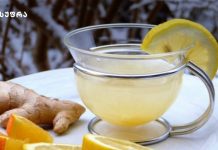 როგორ მოვამზადოთ ჯინჯერის ჩაი – 3 მეთოდი Glass mug of lemon tea with a lemon wedge on the rim, on a white surface with ginger and orange slices nearby