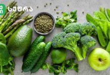 Მწვანე ფერის სარგებელი კვებაში Assortment of green fruits and vegetables on a gray surface: spinach, avocado, cucumber, broccoli, peas, asparagus, lime, and a green apple, with a bowl of peppercorns.