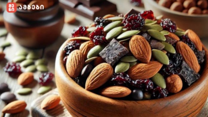 Wooden bowl filled with a snack mix of almonds, pistachios, pumpkin seeds, dried cranberries, and chocolate chunks.
