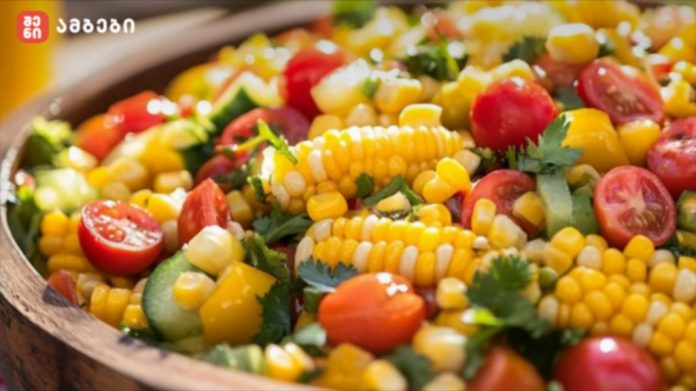 Colorful corn salad with cherry tomatoes, cucumber, bell peppers and fresh herbs in a wooden bowl