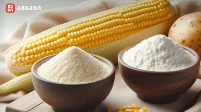 Two wooden bowls filled with flour in front of a corn cob and kernels on a wooden surface.
