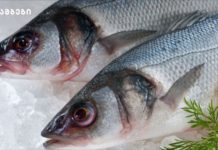 თევზი -როგორ უნდა შევარჩიოთ? Two fresh whole fish on crushed ice with a lemon slice and dill garnish in a display.