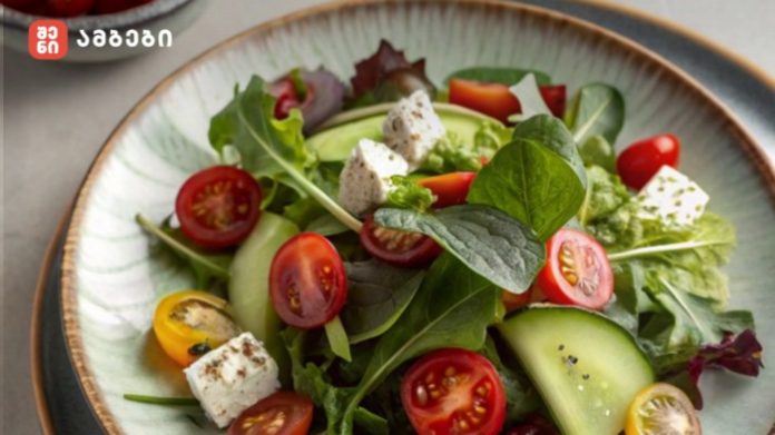 Colorful mixed salad in a ceramic bowl: greens, cucumber, cherry tomatoes (red and yellow), and feta cheese cubes.