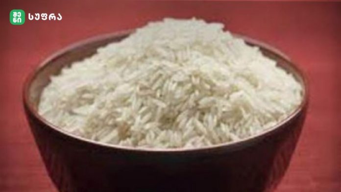 Dark bowl piled high with fluffy white rice on a red surface.