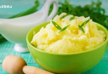 როგორ მოვამზადოთ იდეალური პიურე Green bowl of mashed potatoes garnished with green chive pieces, with a white gravy boat in the background.