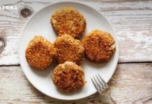 ვეგეტარიანული სოკოს კატლეტები Five crispy, breaded croquettes arranged on a white plate atop a rustic wooden table, with a fork nearby.