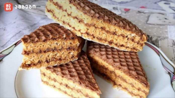 Stack of chocolate wafer cookies with cream filling on a plate, cut into pieces.