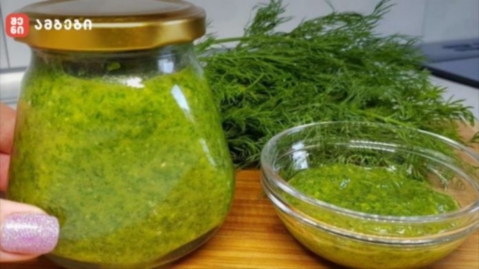 shenisupra-kamis-sousi-1024x575 Jar of bright green pesto with a gold lid beside a glass bowl of pesto on a wooden surface, with fresh dill in the background.