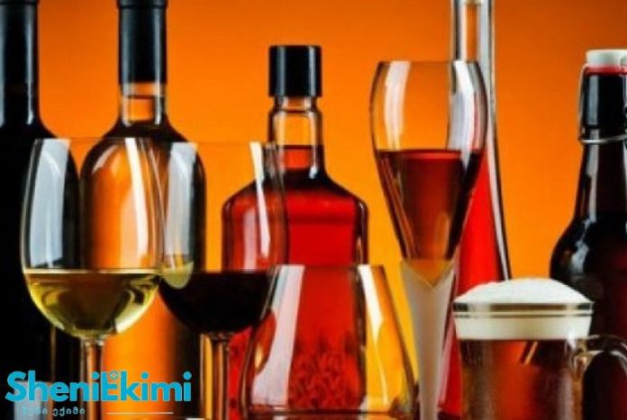 Assorted liquor bottles and glasses on a warm orange background.