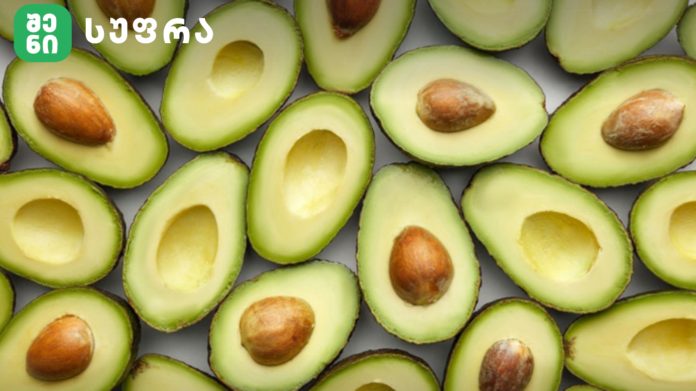 Close-up of avocado halves with bright green flesh and brown pits, with a green logo in the top-left.