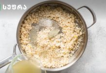 ბრინჯი – პოპულარული მარცვლეულის მომზადების ახალი ვარიაციები Metal pot of rice with a bay leaf, broth being poured in from a pitcher nearby.
