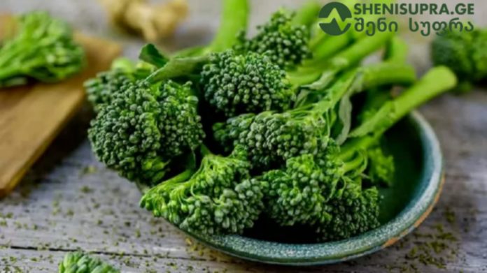 Fresh broccoli florets piled on a ceramic plate, ready for cooking on a wooden table.