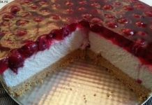 ალუბლის ჩიზქეიქი- გამოცხობის გარეშე Round cake with a glossy cherry topping, white mousse layers, and a crumb crust; a wedge has been removed to show the interior.