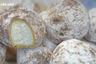 Powdered sugar–dusted donuts with pale yellow filling, stacked together; a bite reveals the filling.