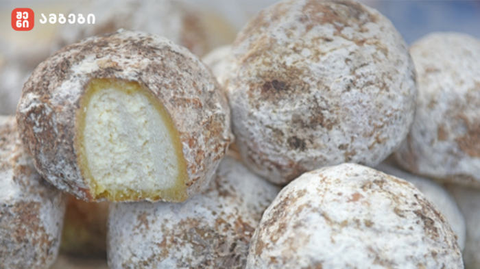 Powdered sugar–dusted donuts with pale yellow filling, stacked together; a bite reveals the filling.