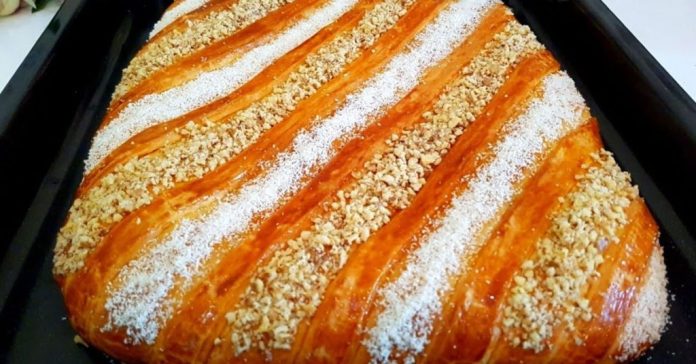 gvezeli Golden braided pastry loaf topped with powdered sugar and chopped nuts in a baking tray, ready for baking or serving