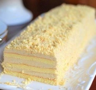 Rectangular multi-layer vanilla sponge cake with pale yellow cream filling and crumb topping on a white plate