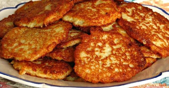 Pile of crispy golden potato pancakes stacked on a white dish.