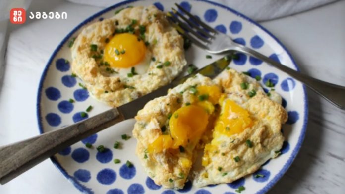 Two egg-in-a-hole portions on a blue-polka-dot plate, garnished with chives, with a knife and fork nearby.