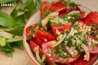 Bowl of chopped tomato salad with onions, dill, and fresh herbs in a ceramic dish.