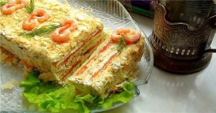 Layered shrimp salad cake on a glass plate, garnished with dill and lettuce leaves.