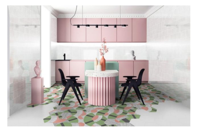 Pastel-pink kitchen with a round ribbed pedestal table centerpiece, black chairs, and pastel-hued cabinetry; geometric green, pink, and white tiled floor.