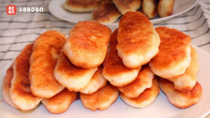 Pile of golden brown fried dough pastries stacked on a white plate.
