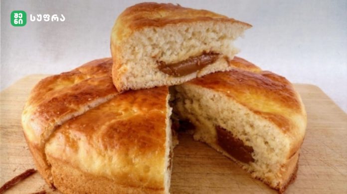 Braided loaf with a jam-filled center, sliced to show soft interior on a wooden cutting board