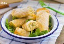 კერძი უჩვეულო ინგრედიენტებით White bowl with blue rim filled with golden spring rolls atop green lettuce on a checkered cloth.