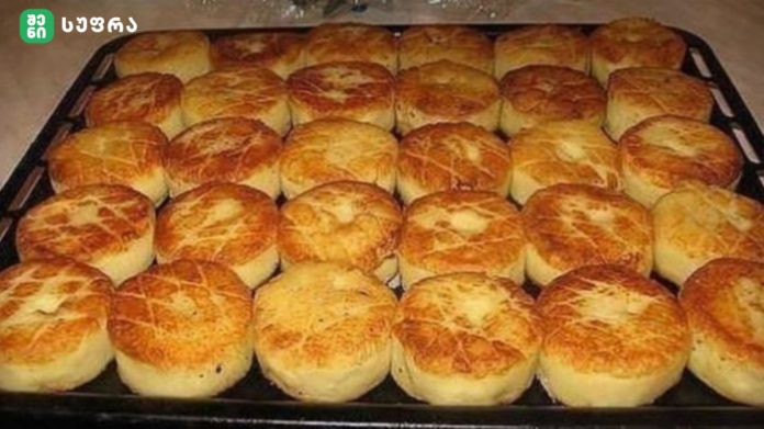 Tray of freshly baked, golden-brown dinner rolls arranged in rows on a baking sheet.