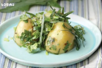 Plate of boiled potatoes topped with fresh herbs on a pale blue plate