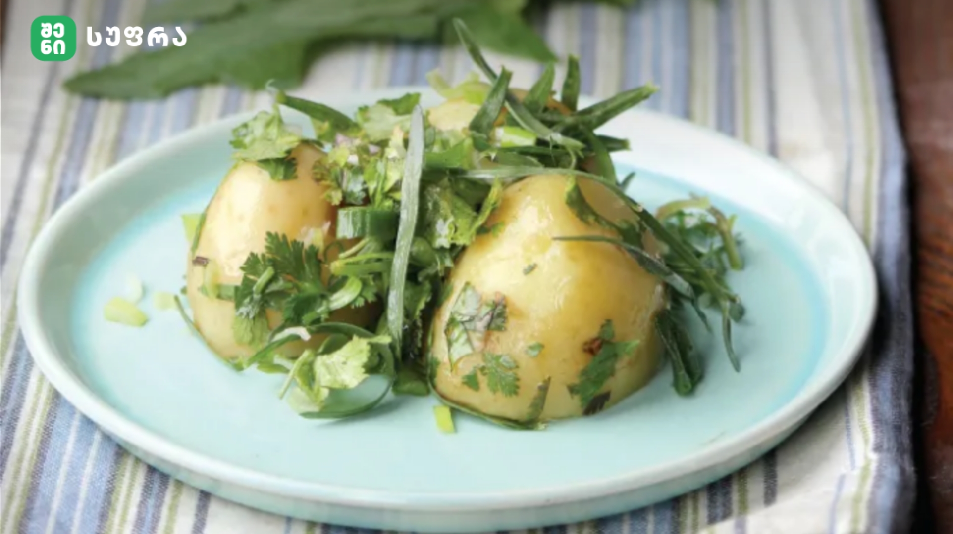 Plate of boiled potatoes topped with fresh herbs on a pale blue plate