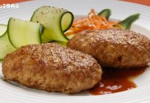 ღუმელში გამომცხვარი კატლეტი ფრანგულად Two browned fried meat croquettes with a red sauce on a white plate, beside cucumber ribbons and shredded carrot.