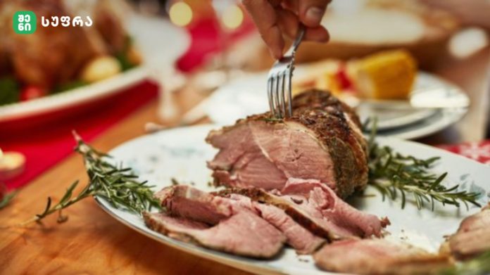 Sliced roast beef on a plate with rosemary sprigs and a fork resting on top of the meat