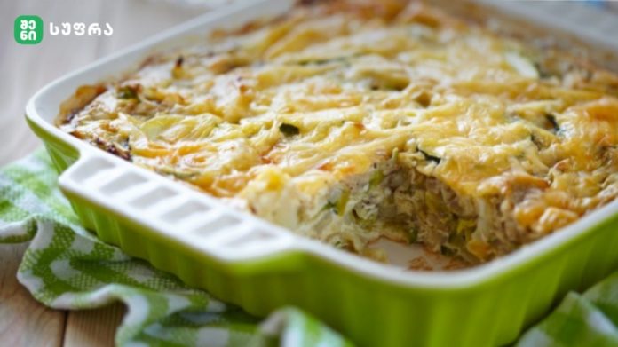 Green ceramic baking dish filled with a cheesy vegetable casserole, fresh from the oven